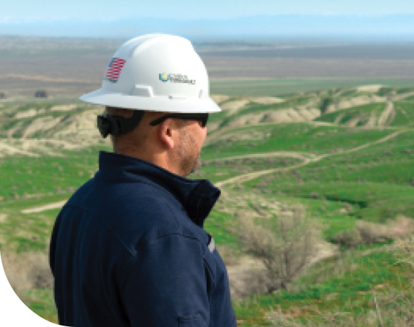 Employee wearing helmet looking at hills